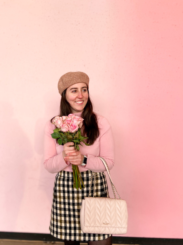 Image description: wool beret, pink sweater, gingham skirt, and pink handbag.