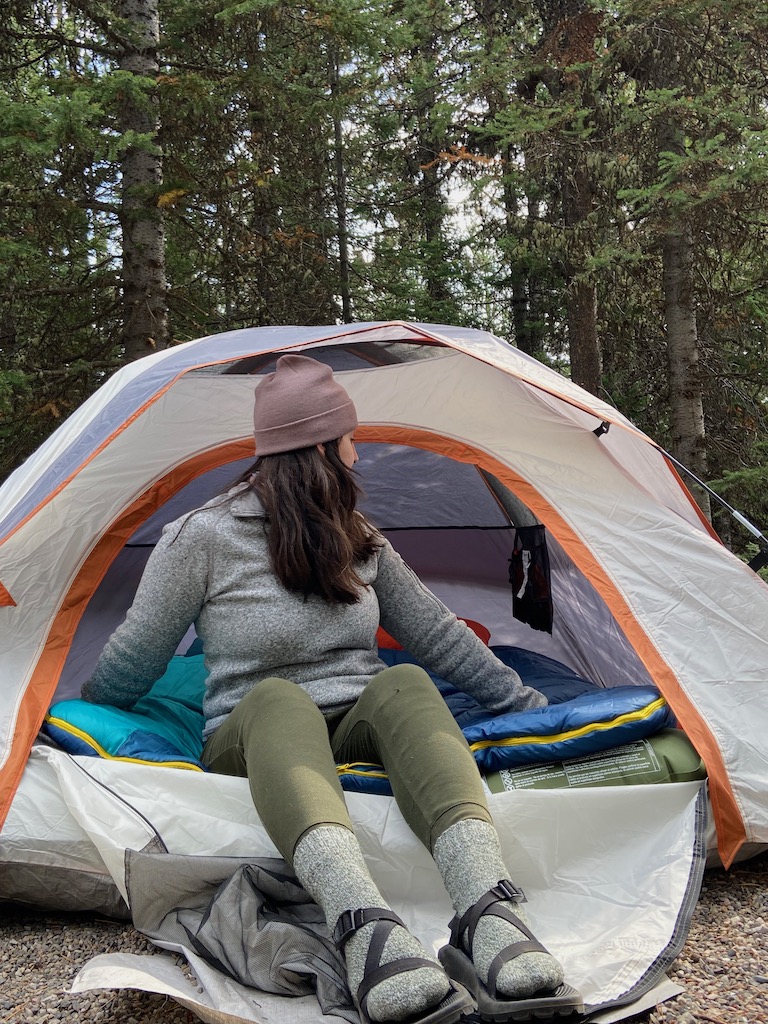 Grand Teton National Park & Jackson Hole Travel diary. Image description: a white woman sitting in the entrance of a tent.